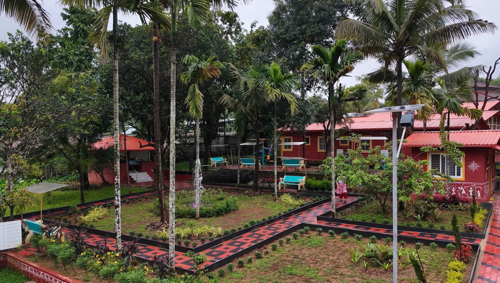 A patterned brick walking path winding through lawns, benches and tall palms on campus